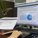 Person analyzing financial data on a computer screen in an office setting.